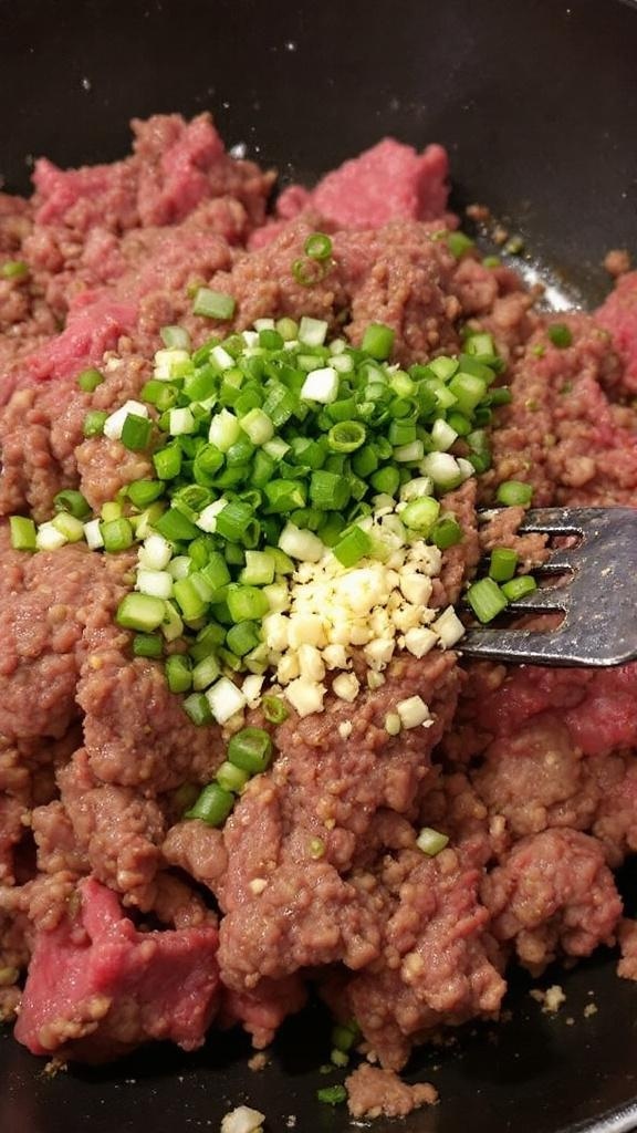 Ground beef with diced onion and minced garlic in a skillet.